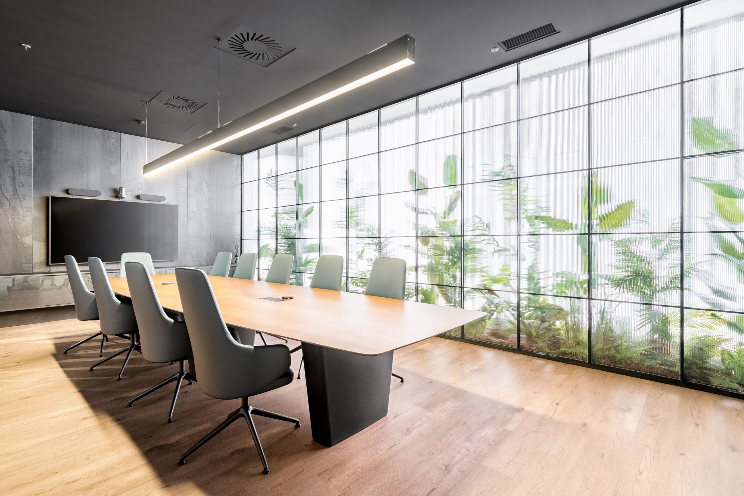 Sala de reuniones acristalada junto a una composición vegetal lineal